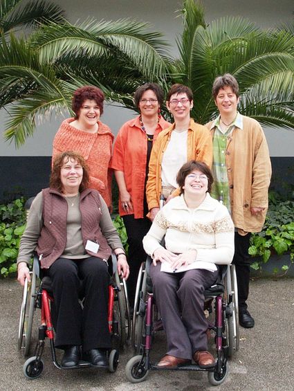 women in wheelchairs and 4 women standing in front of a palm tree