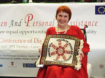 Dinah Radtke presenting a cross stitch which shows the logo from Disabled Peoples International