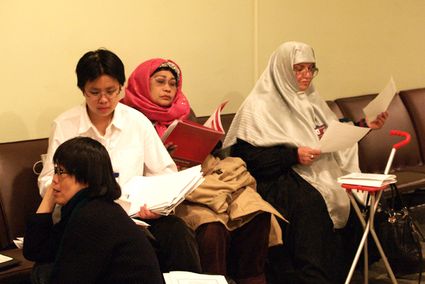 participants, some wearing headscarf, reading papers